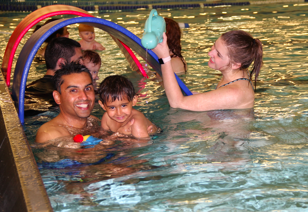 Father holds child in the pool. 